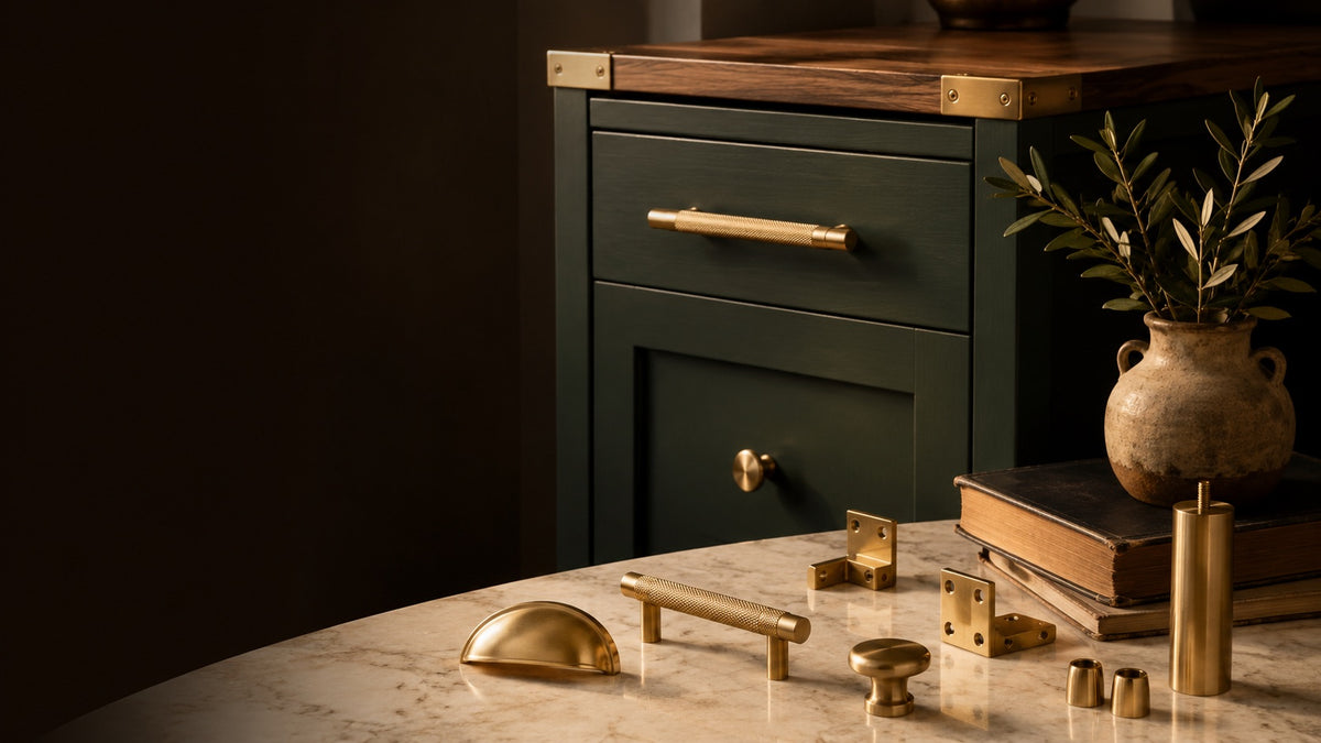 Solid brass cabinet hardware on marble beside a dark green cabinet